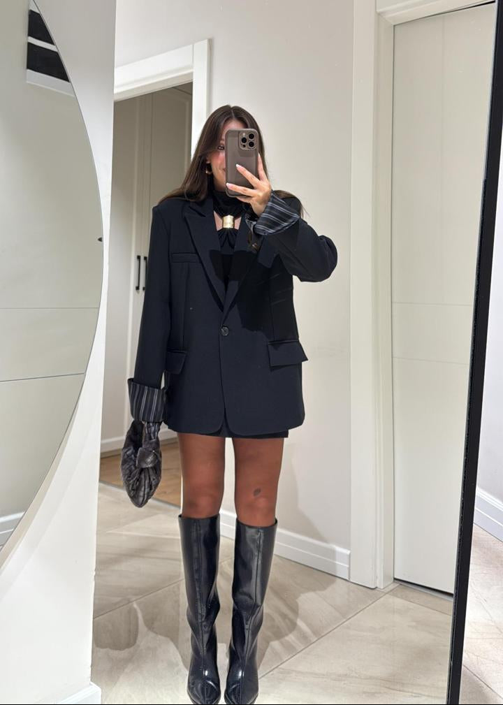 Ce blazer oversize pour femme, d’une élégante teinte bleu marine, est une pièce moderne et polyvalente, parfaite pour un look décontracté chic ou plus habillé. Sa coupe ample et légèrement structurée offre un confort optimal et une silhouette contemporaine.
Il présente un col à revers classique et une fermeture à un seul bouton foncé.

La particularité de ce blazer réside dans sa doublure rayée (blanc et marron/rose pâle), qui devient visible lorsque les manches sont retroussées ou lorsque le blazer est lég